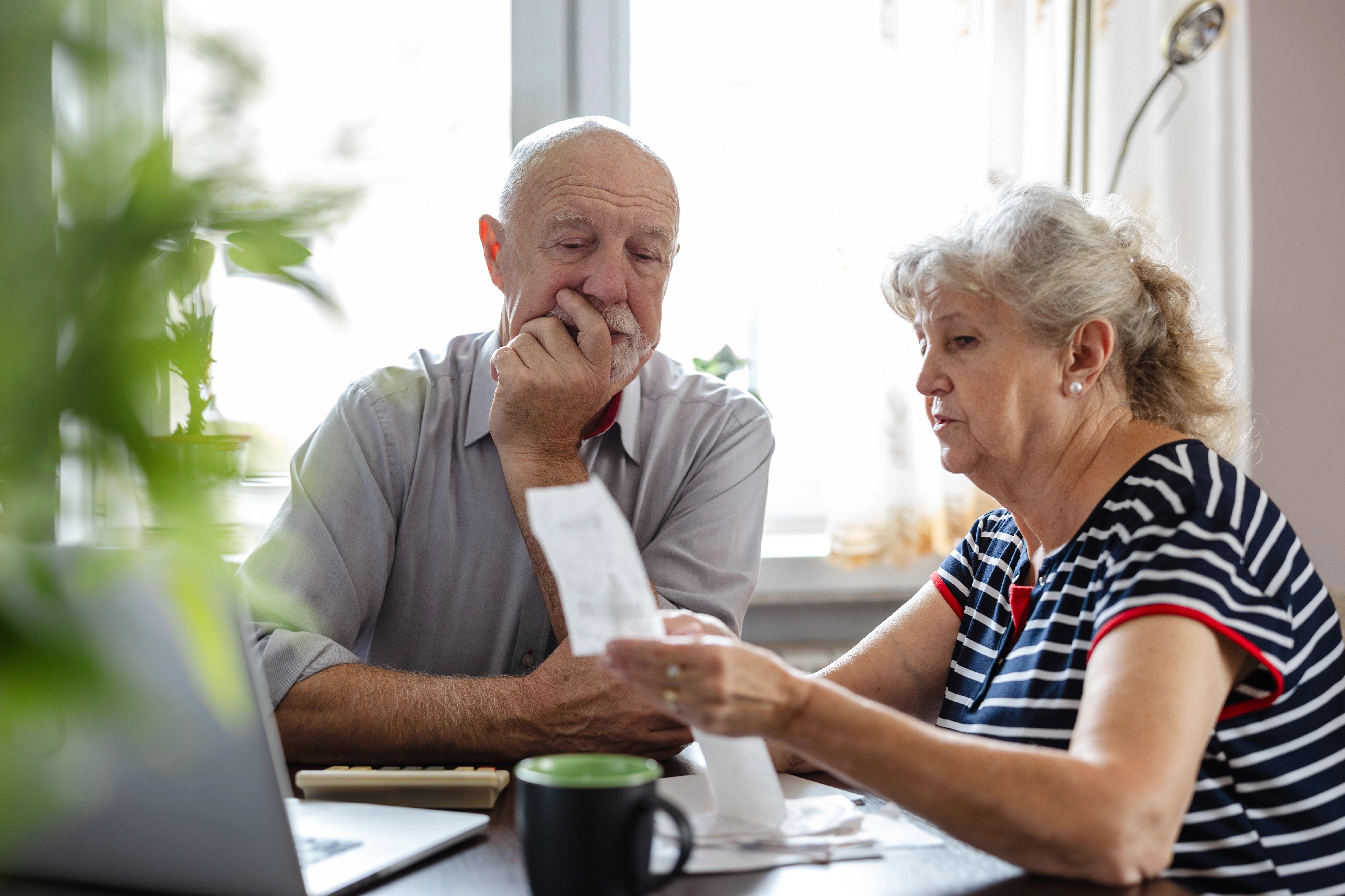 An older couple discussing household finances together at a table.