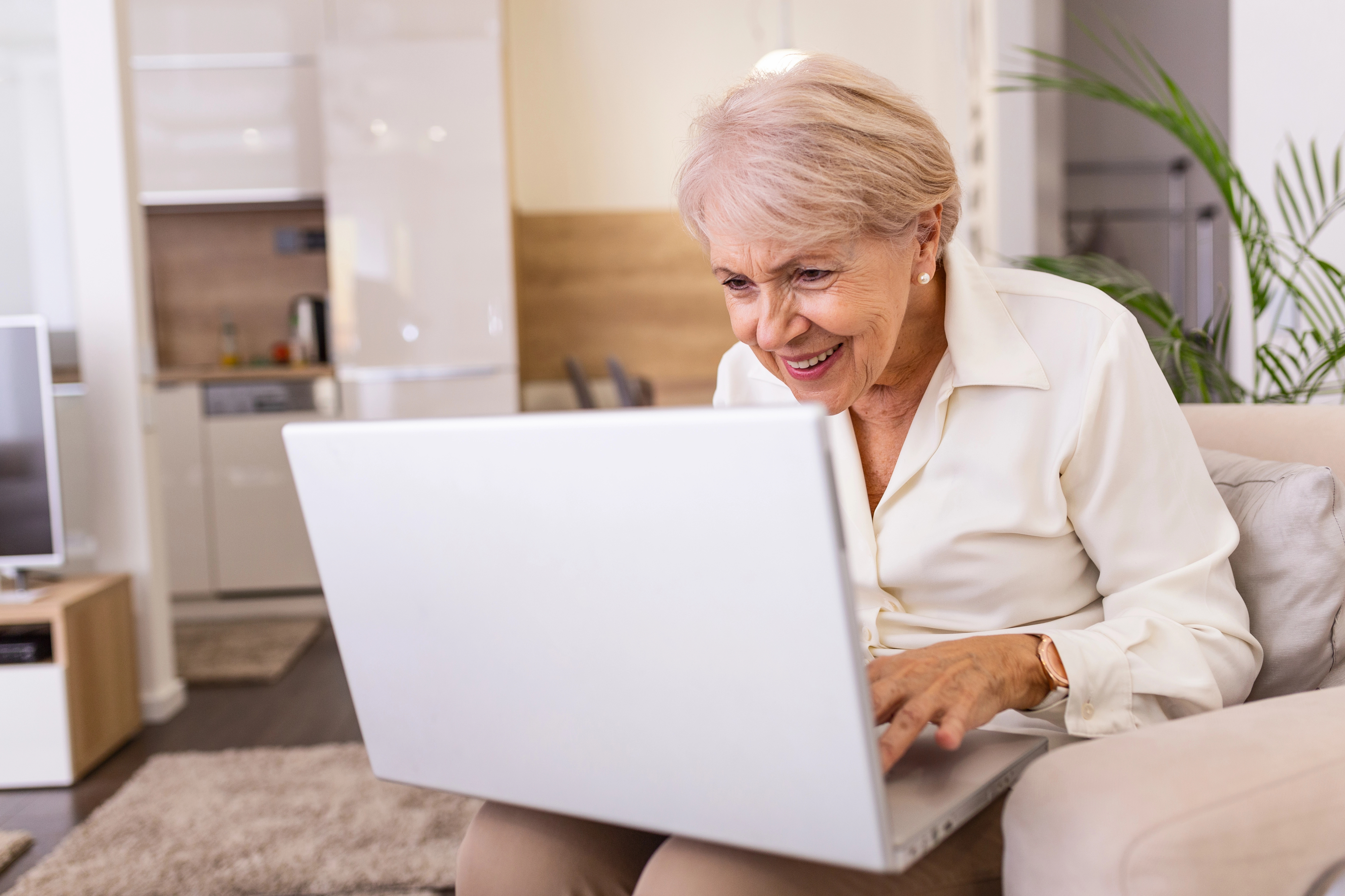 A senior woman using a laptop at home while researching coverage options.